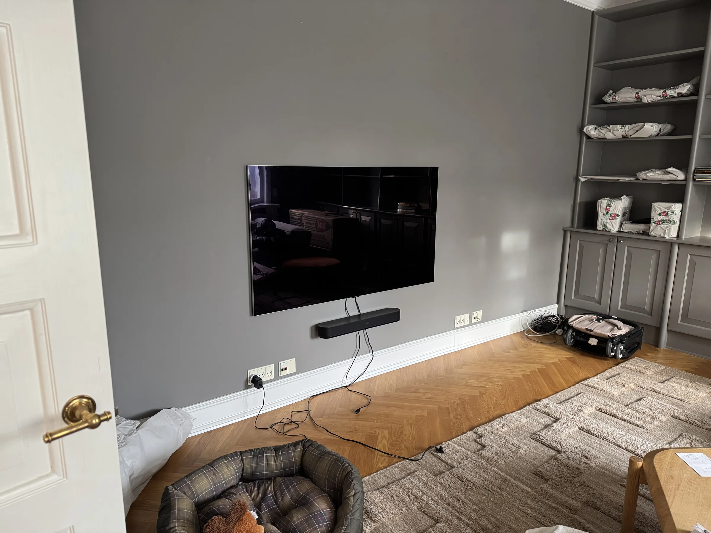 Wall-mounted TV finished neatly on a grey living room wall in a Copenhagen apartment